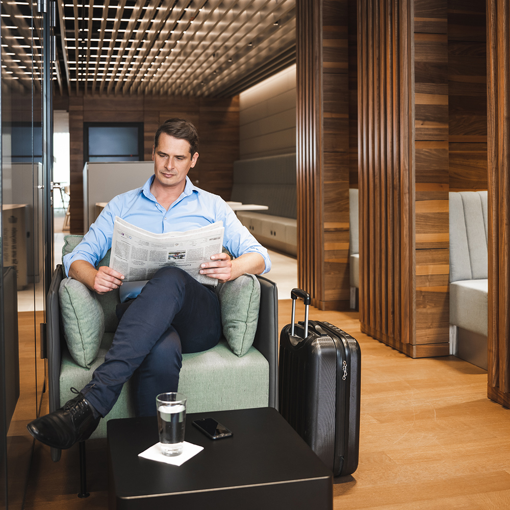 Man reads newspaper in lounge.